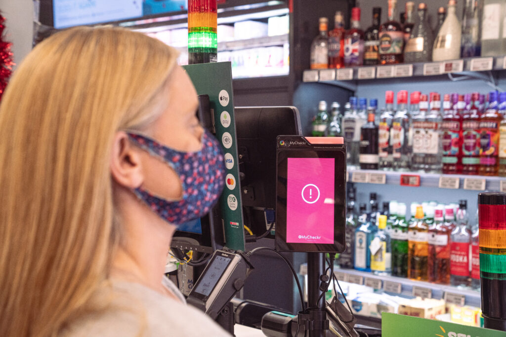 Mujer con mascarilla delante de una tecnología de estimación de la edad