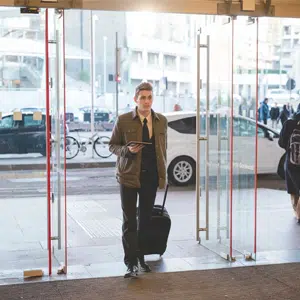 Hombre atravesando una puerta de cristal para entrar en un edificio